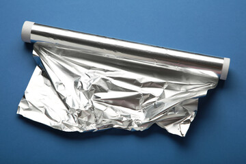 Roll of aluminum foil on dark blue background.