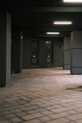 Long tunnel with columns in modern city architecture with low lights and grey colors with tile on the frloor and electricity shield room doors in front