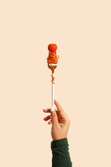 Girl holding fork with noodles and tomato.
