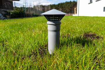 A gray vent pipe from a household septic tank without a drain located in the garden.