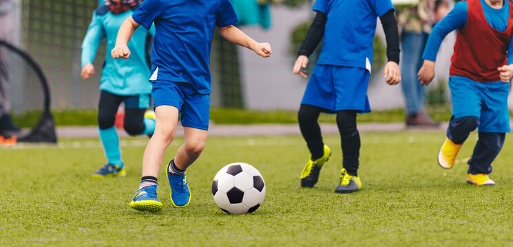 Kindergarten children playing a soccer game at the football pitch. Group of little kids running and kicking football ball