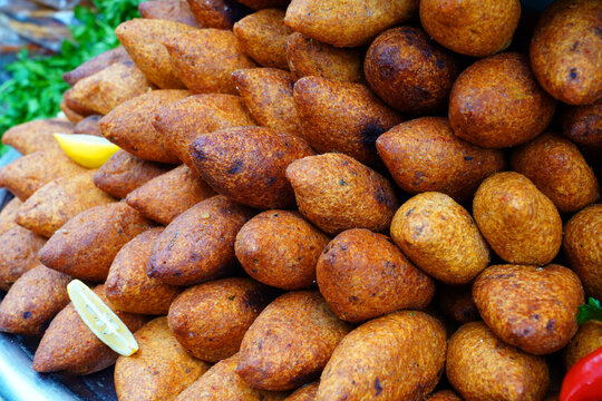 Deep fried kibbeh of ground beef meat mixed with bulgur, stuffed with fried minced meat with pine nuts on a clay plate on wooden board  i&ccedil;li k&ouml;fte ler     