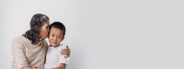 kiss the cheek, Asian grandson and grandmother people sitting together at desk.