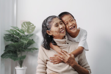 Hugging, love, valentine, Asian grandson and grandmother people sitting together at desk.