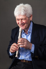 Portrait of an elderly musician in a dark suit on a dark background. 