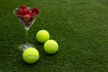 Strawberries and tennis balls on grass