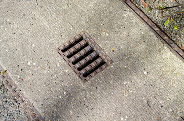 A sewer pit with a metal grate on a street in Germany.