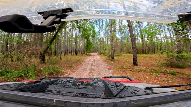 Passenger pov riding in a side by side 4x4 off road vehicle through nature trails