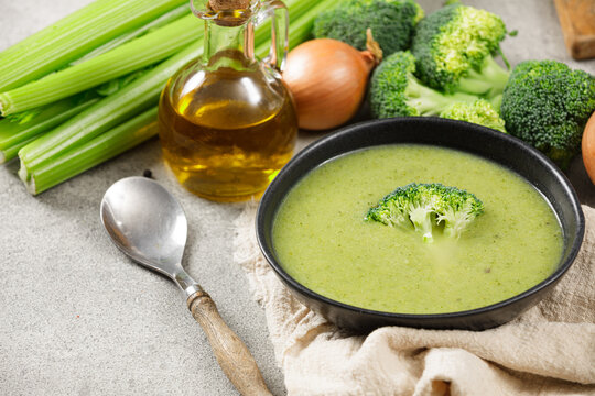 Fresh broccoli soup in blacke plate on gray background