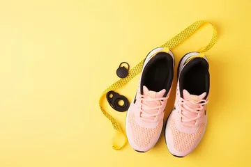 Fotobehang Sapatos esportivos femininos, halteres, fita de fitness, roupas esportivas, rolo de fitness na vista superior de fundo amarelo © Alexandre