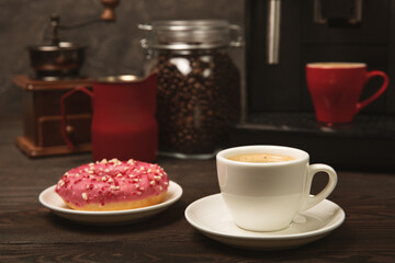 Fragrant delicious espresso coffee with pink strawberry donut, coffee machine on brown texture table. Good morning concept. Morning coffee. Sweet table. Colorful berry buns.Top view.