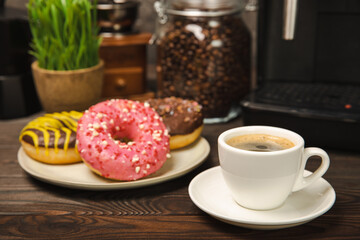 Fragrant delicious espresso coffee with pink strawberry donut, coffee machine on brown texture table. Good morning concept. Morning coffee. Sweet table. Colorful berry buns.Top view.
