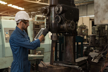 Male factory worker maintenance machine in industrial factory, working with digital tablet computer. Male technician inspecting lathe machine. Male engineer repairing machine in workshop
