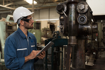 Male factory worker maintenance machine in industrial factory, working with digital tablet computer. Male technician inspecting lathe machine. Male engineer repairing machine in workshop