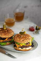 Double Cheeseburger with tomato and lettuce on a plate and two glasses of bier.