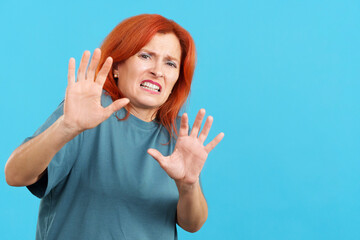 Redheaded mature woman gesturing with the hands in fear