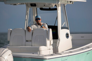 Man on a center console boat talking on a radio.