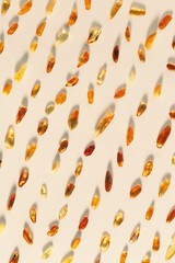 Natural Amber texture background, yellow orange color stones with glare shadows on beige. Natural gemstone mineral material for jewelry. Transparent pieces gem Amber, vertical photo pattern