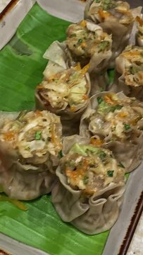 A closeup of vegetarian momos or dumplings on a plate with vegetable salad