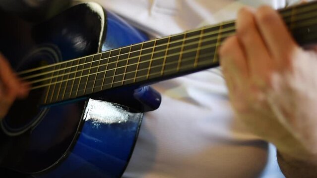 Close up in hand of person playing a blue guitar