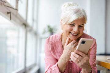 Smiling senior woman using smartphone 
