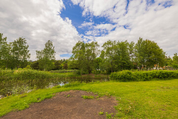 Beautiful nature landscape backgrounds. Lake surrounded with green trees on blue sky with white clouds background. Sweden. 