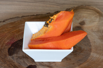 Papaya en recipiente blanco sobre tronco de madera - Papaya in white bowl on wooden log