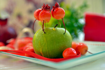 shana tovah!  A green apple decorated with small pomegranates with drops of honey on top of a...