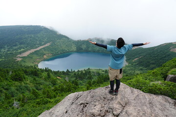 Obraz premium Happy Traveler with Arms Raised Watching Sunrise Above the Clouds