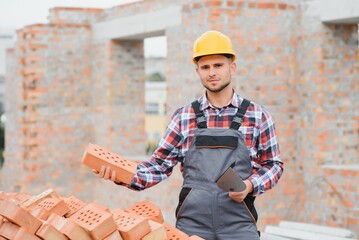 construction mason worker bricklayer installing red brick with trowel putty knife outdoors.