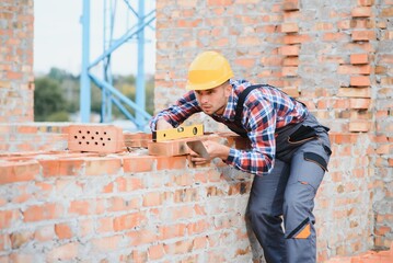 Construction worker man in work clothes and a construction helmet. Portrait of positive male builder in hardhat working at construction site.