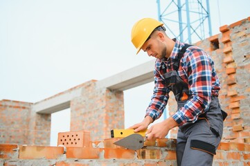 Installing brick wall. Construction worker in uniform and safety equipment have job on building