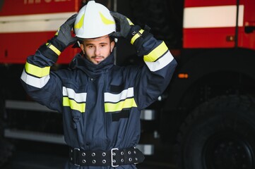 Fireman (firefighter) in action standing near a firetruck. Emergency safety. Protection, rescue from danger.