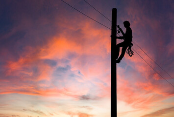Silhouette of Electrician repairing wire on electric power pole at the sunsetbackground. - obrazy, fototapety, plakaty
