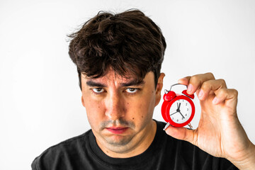 Angry man holding a red clock with one hand and frowning. Mention the dissatisfaction with...