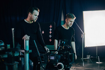 Director of photography with a camera in his hands on the set. Professional videographer at work on filming a movie, commercial or TV series.