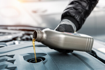 Close-up driver hand holding small bottle can pouring synthetic motor oil in diesel or petrol...
