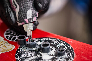 Close up tattoo machine. Tattooing. Man creating picture on his arm by a professional tattoo artist.