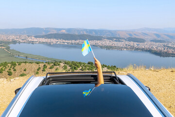 Woman holding Sweden flag from the open car sunroof,  window driving along the serpentine road in...