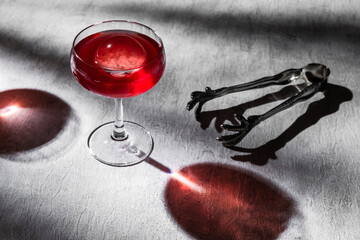 A red cocktail in coupe glass with ice sphere shot on grey background with hard light and shadows