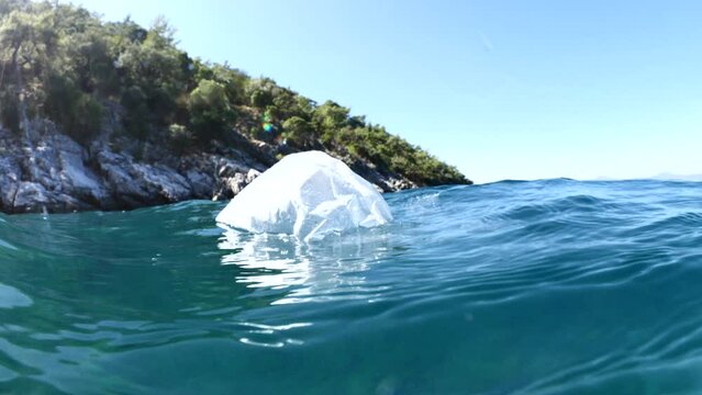 plastic bag split shot underwater like iceberg pollution of oceans half surface half underwater with green trees