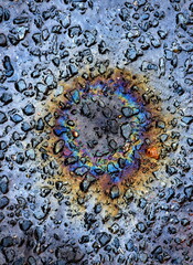 Fototapeta na wymiar Rainbow circle on the rough surface of asphalt.