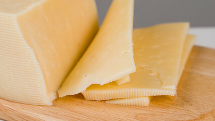 Slices of yellow cheese on wooden board