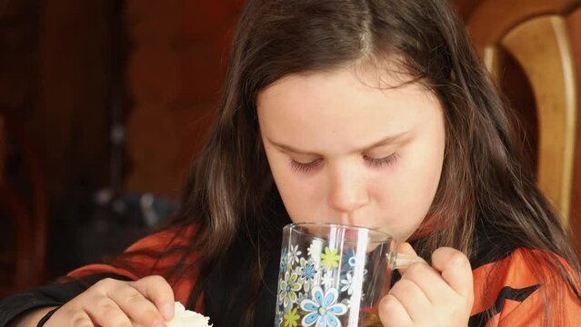 Concentrated, passionate fat little brunette girl chewing and champing shawarma or sandwich and drink hot tea. Overeating and excess fat, obesity and violation of hormones and overweight. Video, 4k