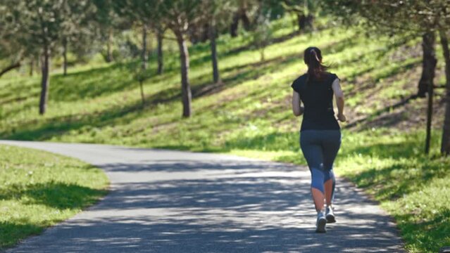 Adult woman jogging in the green park