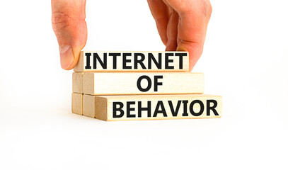 Internet of behavior symbol. Concept words Internet of behavior on wooden block on a beautiful white table white background. Businessman hand. Business Internet of behavior concept. Copy space.