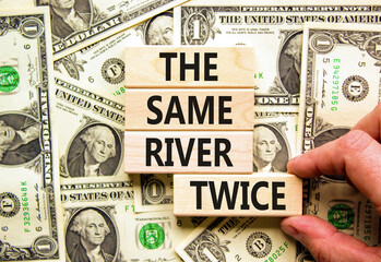 The same river twice symbol. Concept words The same river twice on wooden block. Beautiful background from dollar bills. Businessman hand. Motivational business same river twice concept. Copy space.