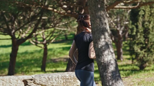 Adult sportive woman in glasses jogging in the green park