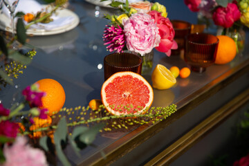 Close up of a wedding table with flowers and citrus decorations outdoor in the sunny summer day.