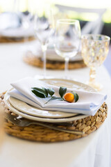 Plates for seating the wedding table with citrus fruit decorations. Selective focus.
